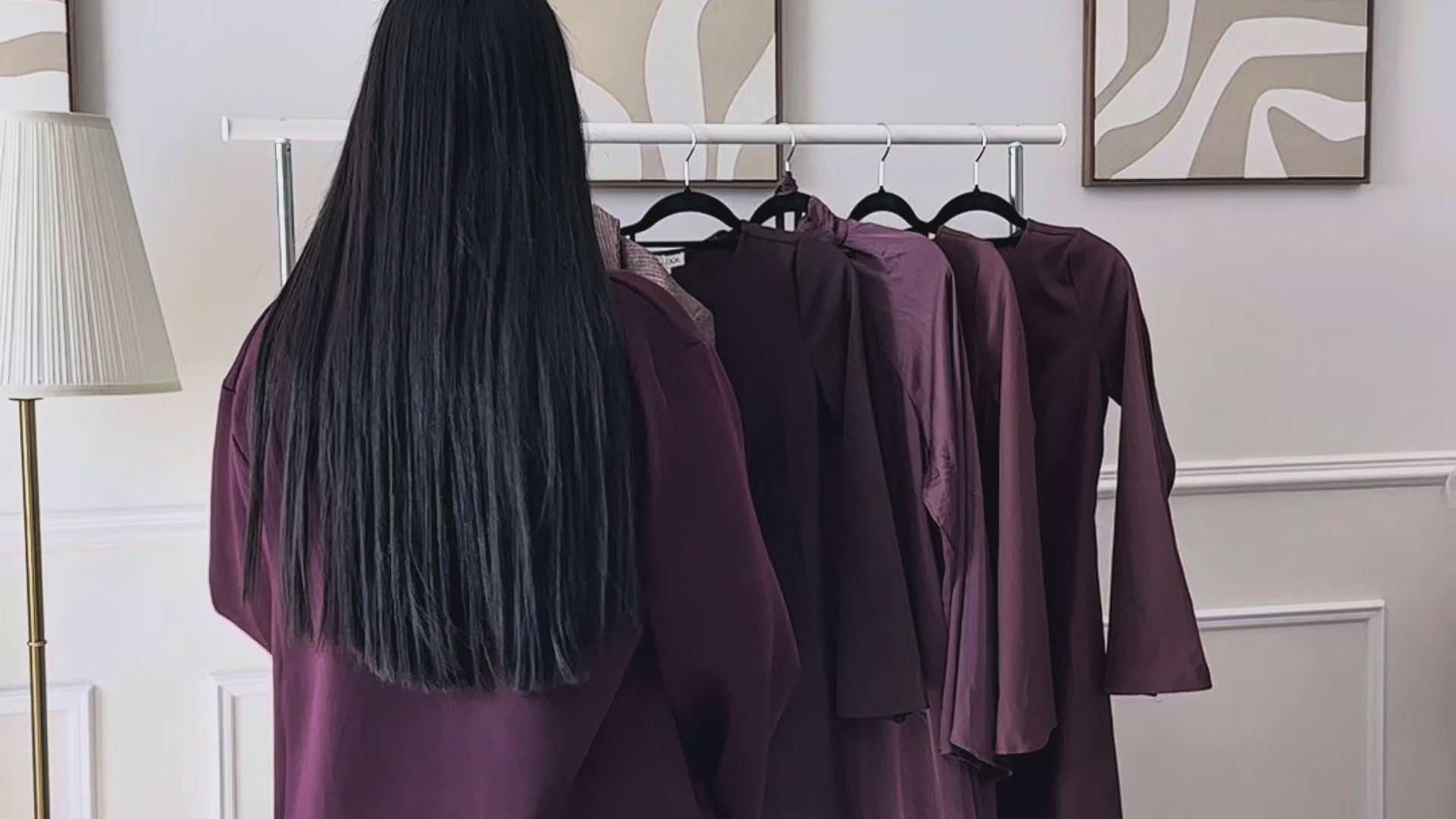 Femme effleurant un portant d’abayas élégantes dans la boutique Layim Collection.